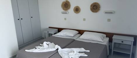 A hotel room with a large bed, two bedside tables, a wardrobe, and decorative wall art.