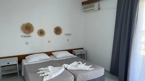 A hotel room with two beds, a small bedside table, a wall-mounted air conditioner, and a window with curtains. - Smart Accomodation Rhodes by GHH (Rhodes)