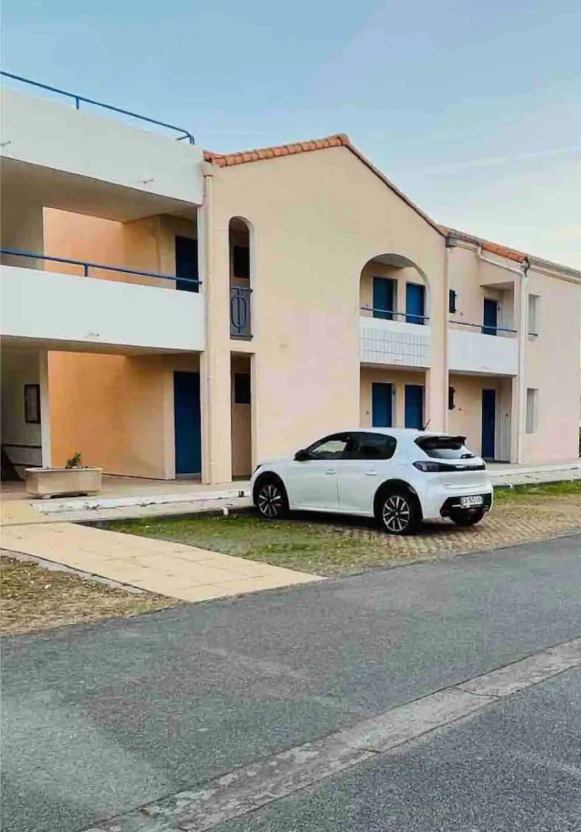 A two-story building with a white car parked in front.