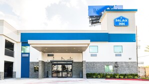 A modern hotel entrance with a blue and white color scheme, a covered entrance, and a sign indicating it is a Palace Inn. - Palace Inn IAH Houston Bush Intercontinental Airport (Humble)