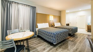 A hotel room with a bed, a desk, and a chair. - Palace Inn IAH Houston Bush Intercontinental Airport (Humble)
