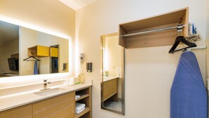 A modern bathroom with a large mirror, wooden vanity, and a towel rack. - Palace Inn IAH Houston Bush Intercontinental Airport (Humble)