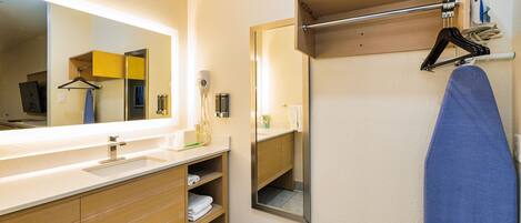 A modern bathroom with a large mirror, wooden vanity, and a towel rack.