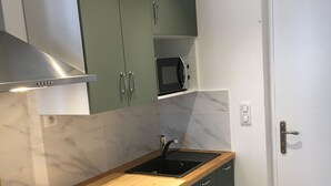 A compact kitchen with green cabinets, a microwave, a sink, a dishwasher, and a stove. - Downtown studio*** with outdoor parking and private, secure bike storage. (Bagnères-de-Bigorre)