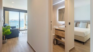 A modern hotel room with a balcony, a sofa, a small table, and a bed. - Arenal Suites Benidorm (Benidorm)