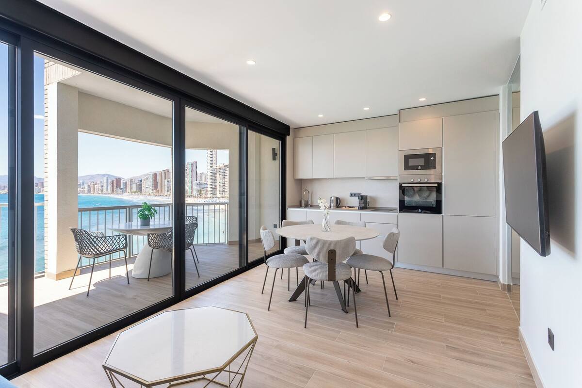 Cozinha moderna com área de jantar e varanda com vista para a cidade.