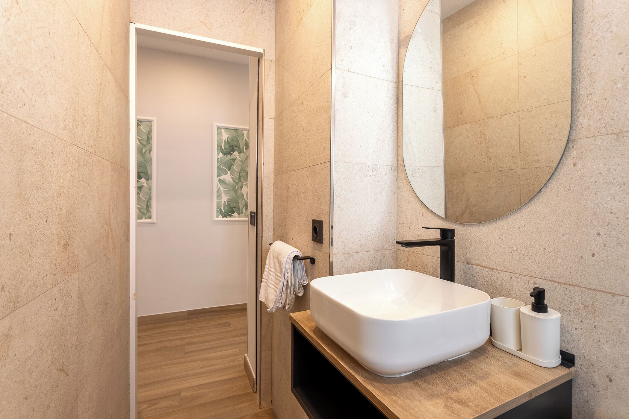 Un baño moderno con un lavabo blanco grande, un espejo y un perchero para toallas.