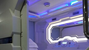 A futuristic room with a control panel, a bed, and a window with a view of the outside. - Bestow Hostel (Kuala Lumpur)