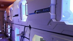 A row of modern, white, modular rooms with built-in digital interfaces on the walls. - Bestow Hostel (Kuala Lumpur)