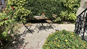 An outdoor seating area with a table and chairs, surrounded by greenery and a gravel path. - Nid Douillet de 45 m2, Centre-ville, 2 Chambres (Trouville-sur-Mer)