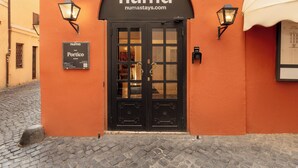 A hotel entrance with a black door, two wall-mounted lamps, and a sign above the door. - Numa Rome Portico (Rome)