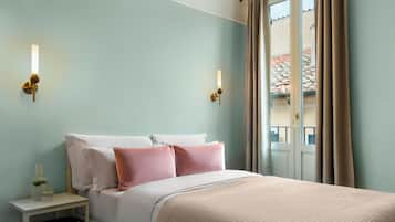 Una habitación de hotel con cama, mesitas de noche y ventana con cortinas.