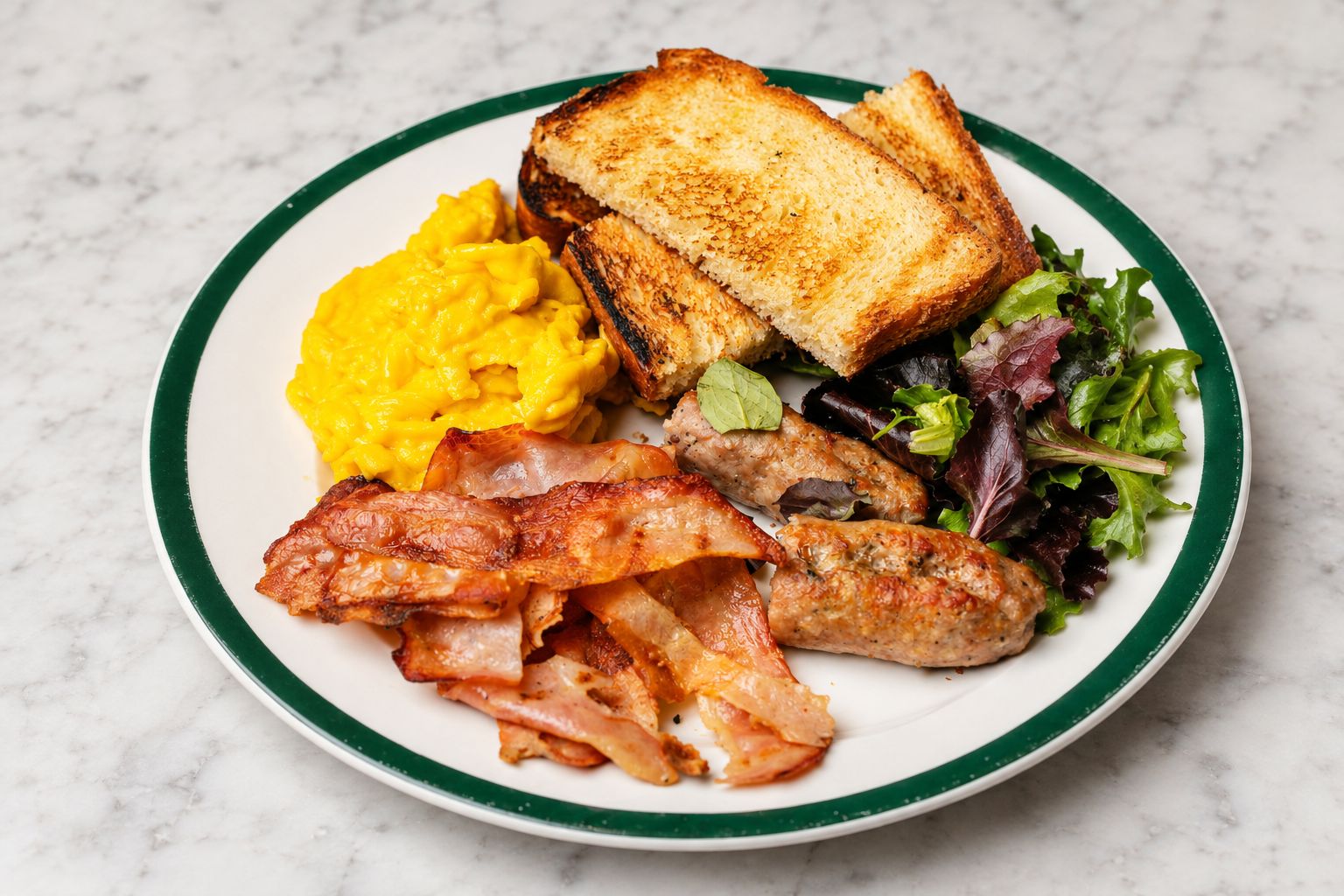 Un plato con huevos revueltos, pan tostado, tocino, salchichas y una ensalada.