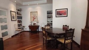 A dining area with a wooden table and chairs, a bookshelf, and a door with frosted glass panels.