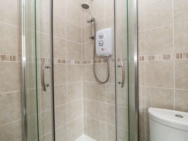 Un box de ducha con paredes de vidrio, cabezal de ducha manual y control remoto.