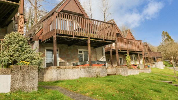 Une maison traditionnelle en bois, avec des fondations en pierre, un balcon et un ciel dégagé.