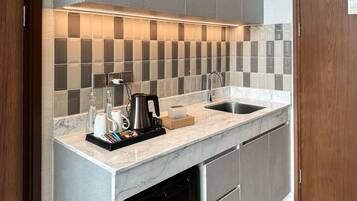 A modern kitchen with a marble countertop, a built-in sink, and a backsplash of square tiles.