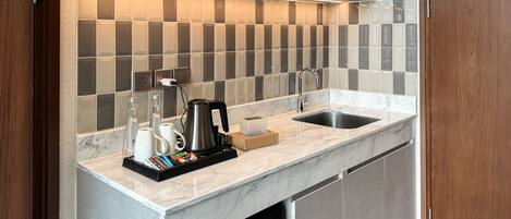 A modern kitchen with a marble countertop, a built-in sink, and a backsplash of square tiles.