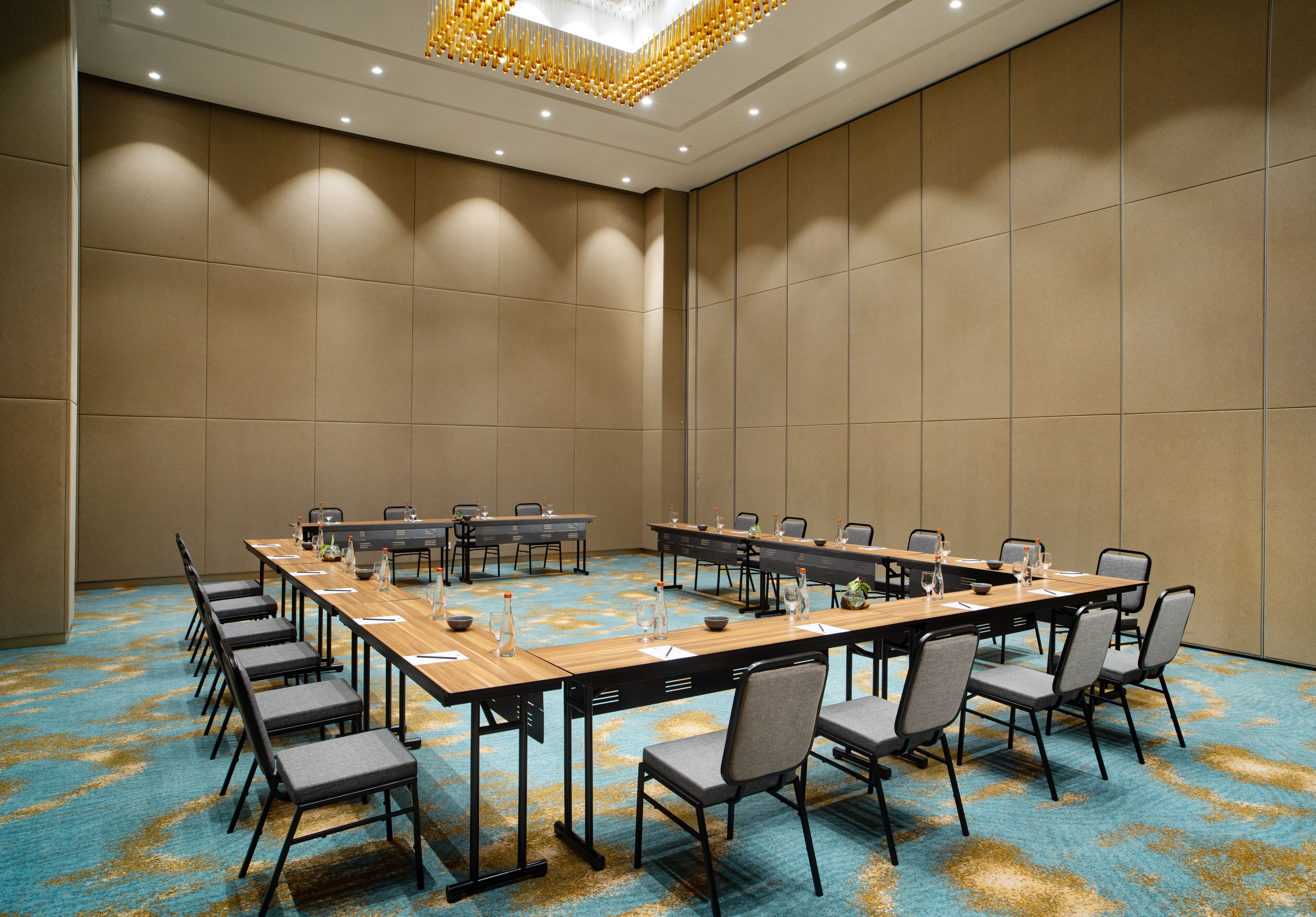 Una sala conferenze con un lungo tavolo, sedie e pavimento rivestito di moquette.