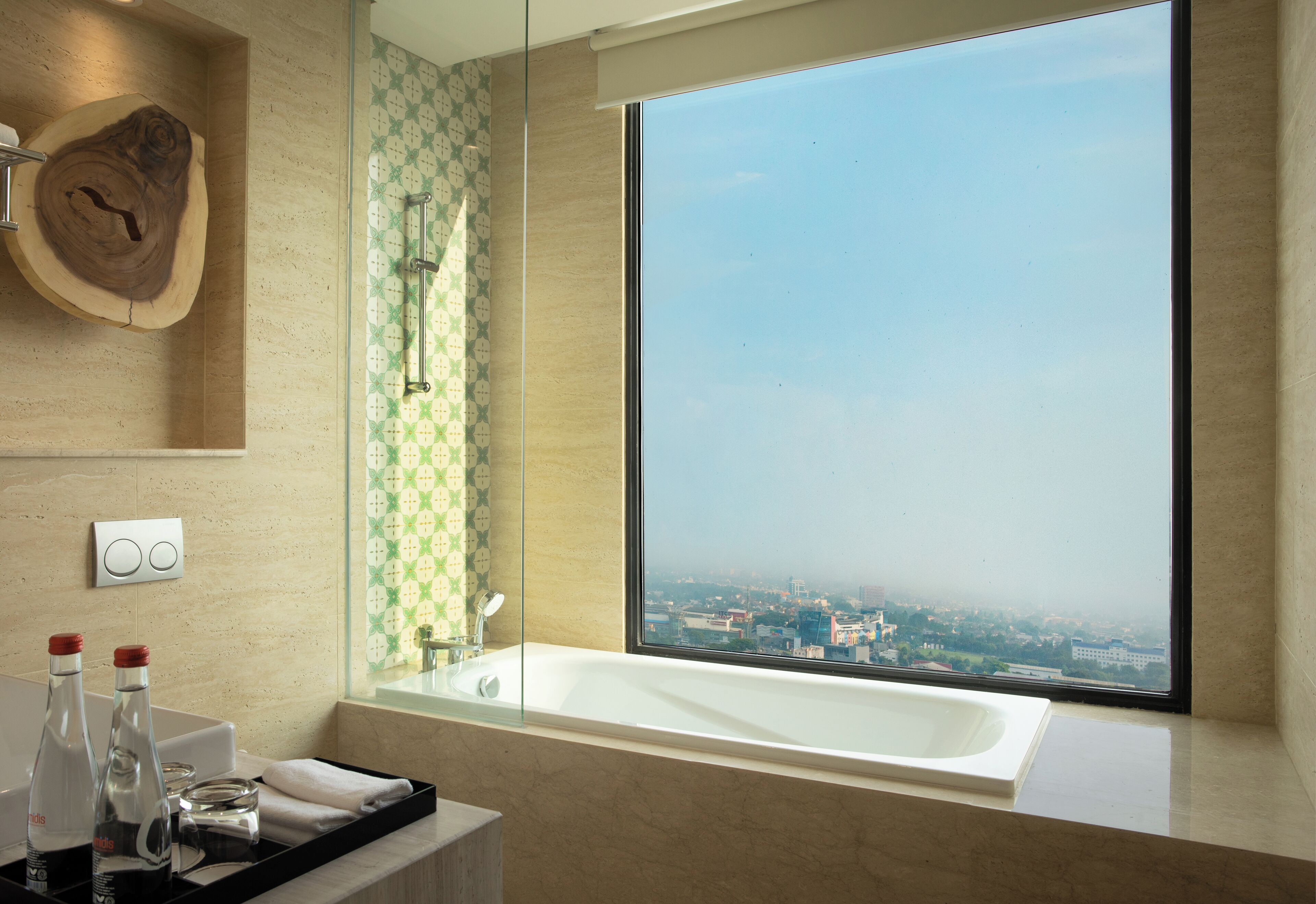 A modern bathroom with a large bathtub, a wooden wall decor, and a view of a cityscape through a large window.