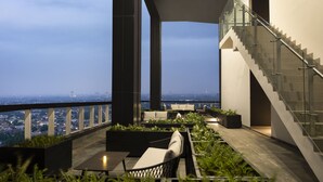 A rooftop terrace with outdoor seating, a staircase, and a city view. - Trembesi Hotel (South Tangerang)