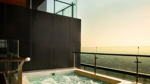 A hot tub with a glass railing overlooking a cityscape. - Trembesi Hotel (South Tangerang)