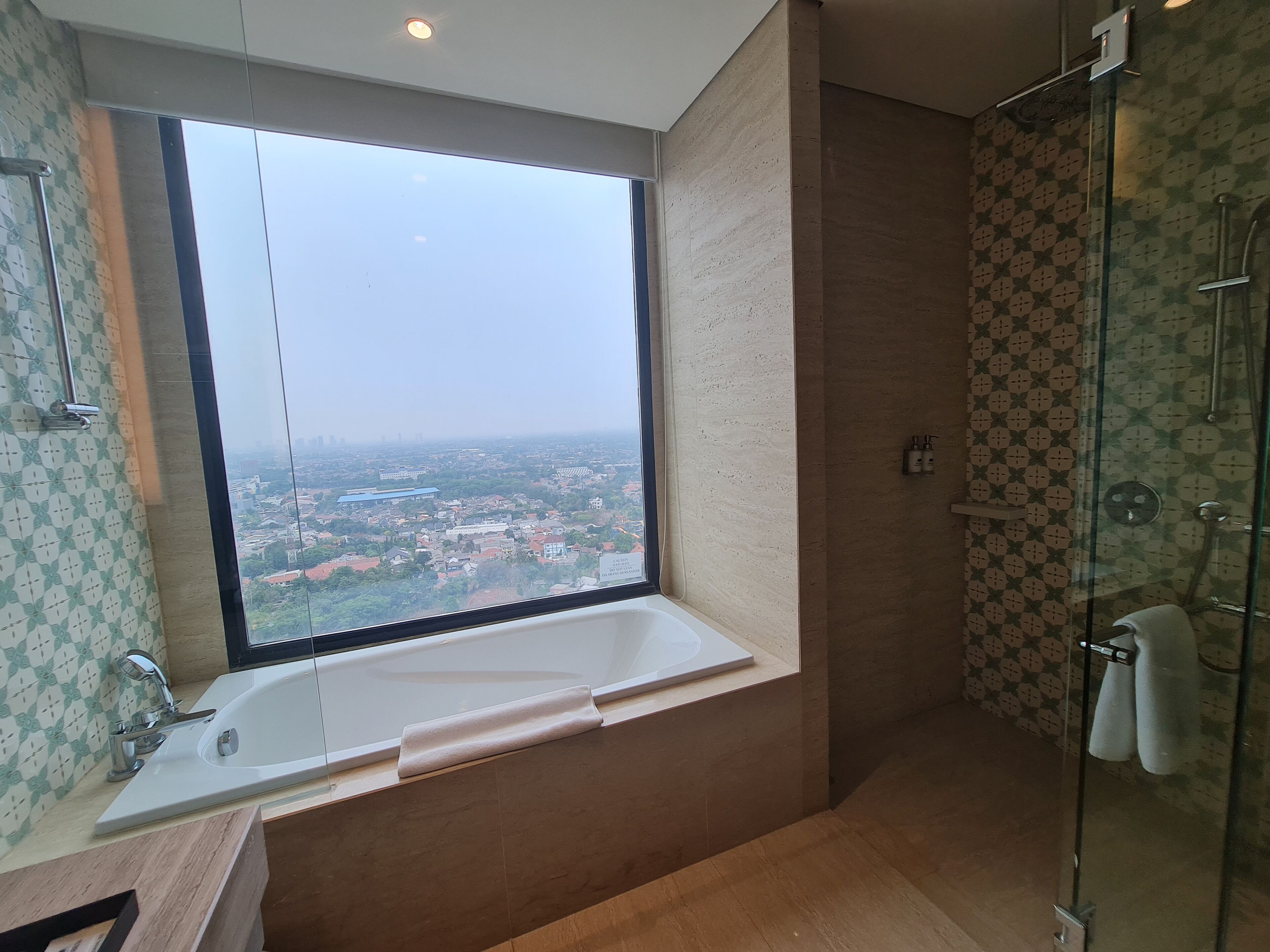 A modern bathroom with a large window, a bathtub, and a shower area.