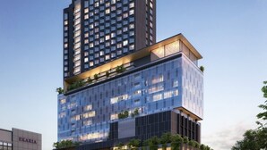 A modern hotel with a prominent 'TREMBESI' sign on the top, featuring a mix of glass and metal facade, and a lower section with a green vertical garden. - Trembesi Hotel (South Tangerang)