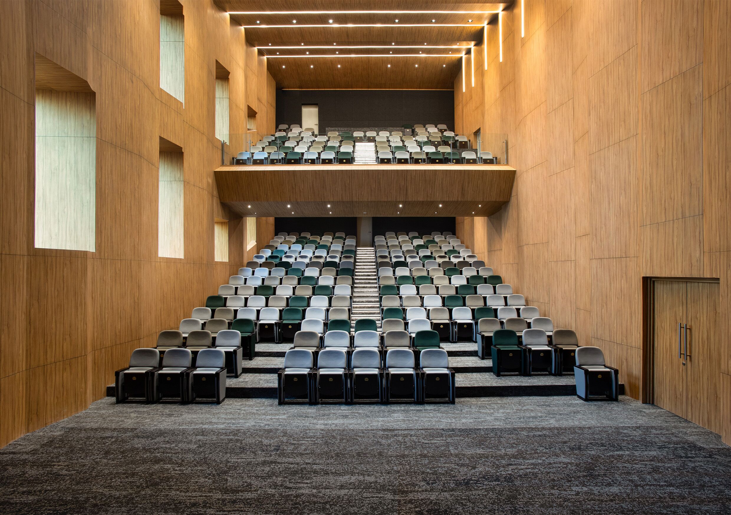 A conference room with tiered seating, carpeted floor, and wooden walls.