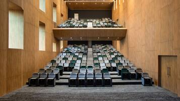 A conference room with tiered seating, carpeted floor, and wooden walls.