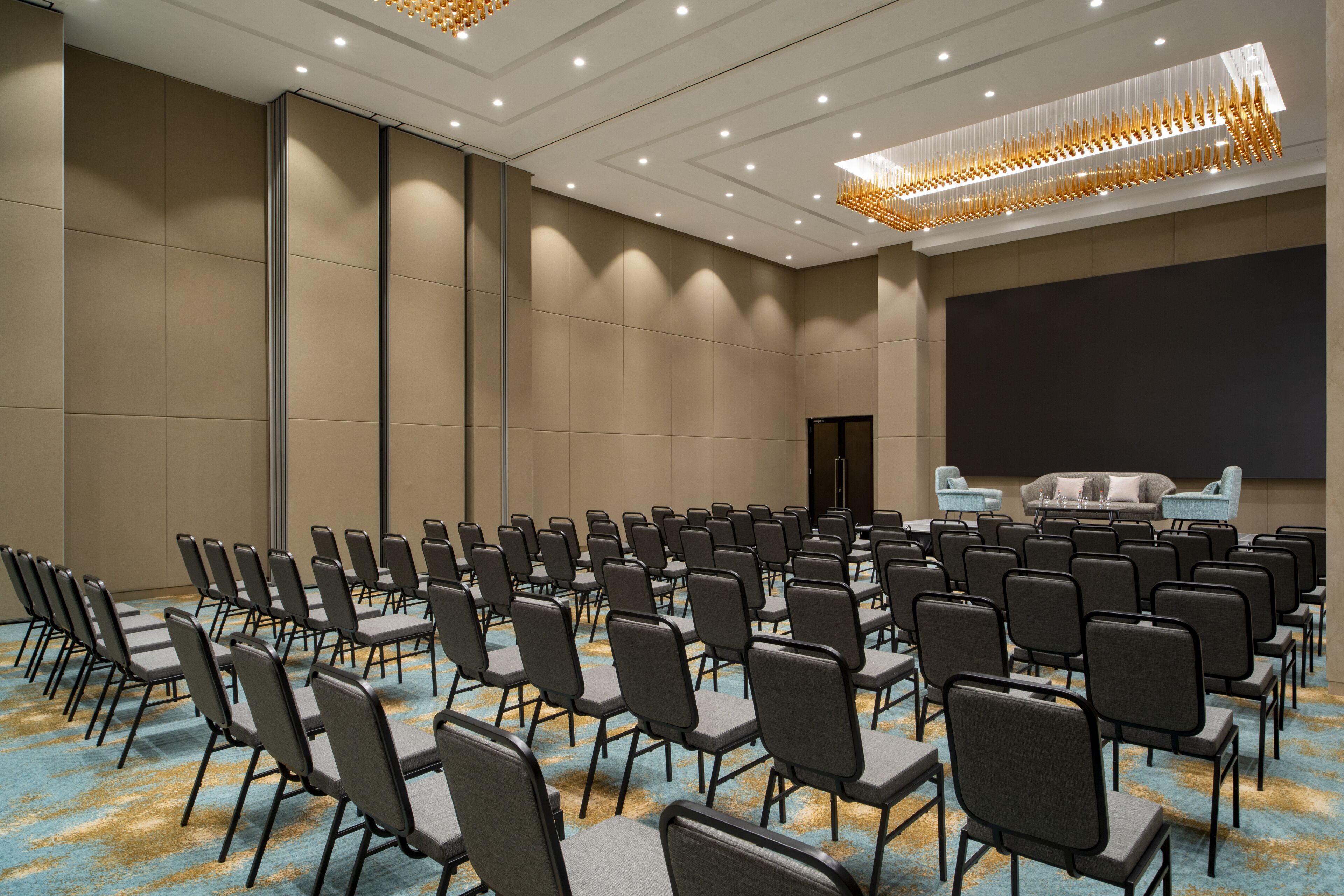 A conference room with rows of chairs, a large screen, and a sofa.