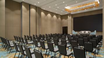 A conference room with rows of chairs, a large screen, and a sofa.