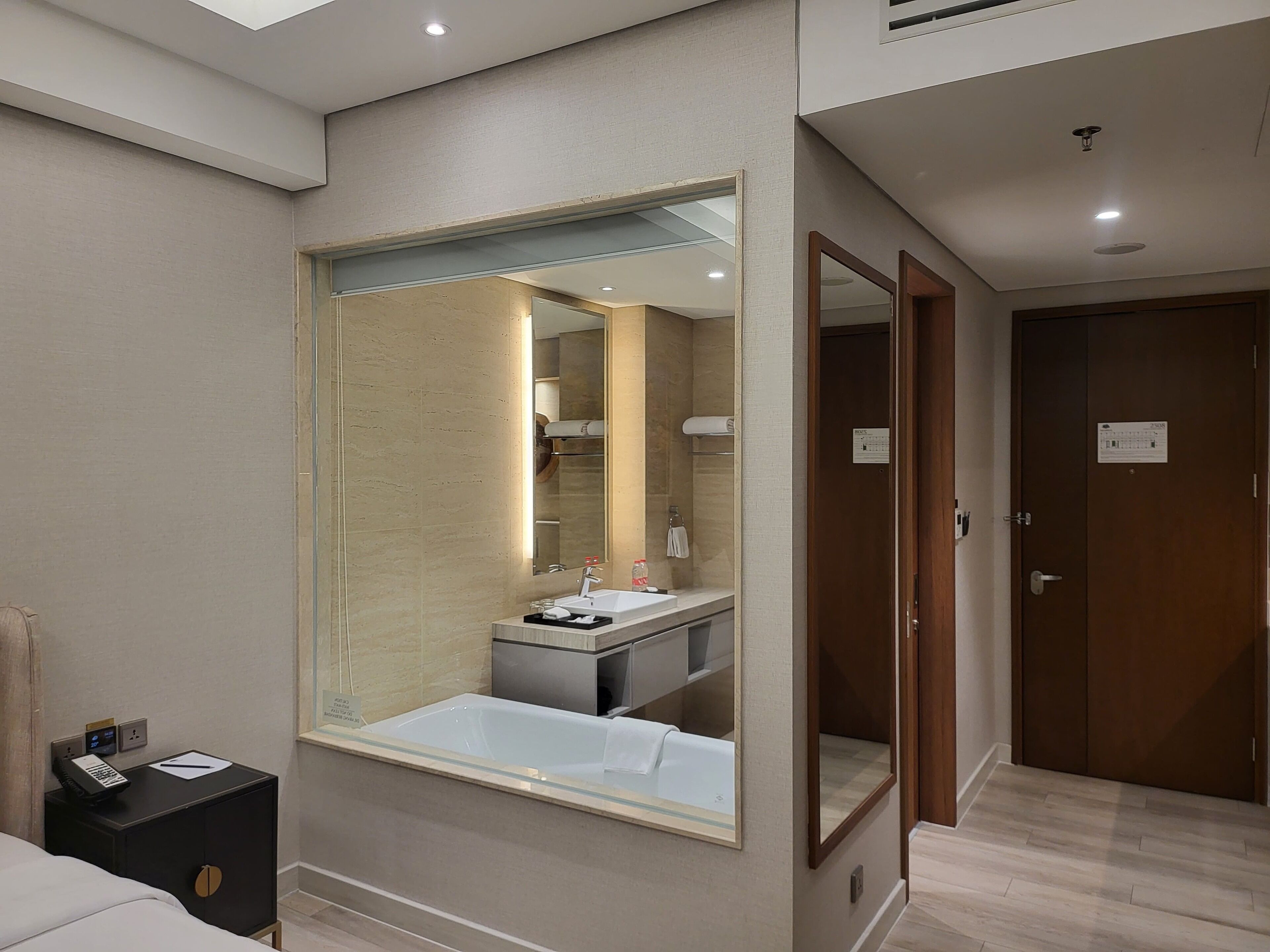 Une chambre d’hôtel avec un grand miroir, un lavabo et une porte en bois.