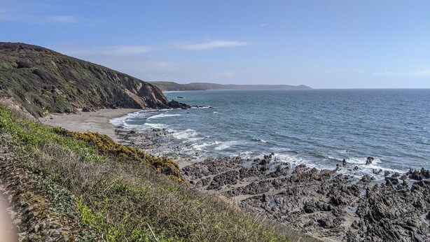 Un paysage côtier caractérisé par un terrain rocheux et une plage.