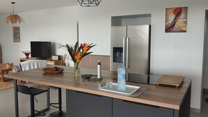 Una cocina moderna con una isla central, un refrigerador empotrado y una zona de comedor con sofá y mesa.
