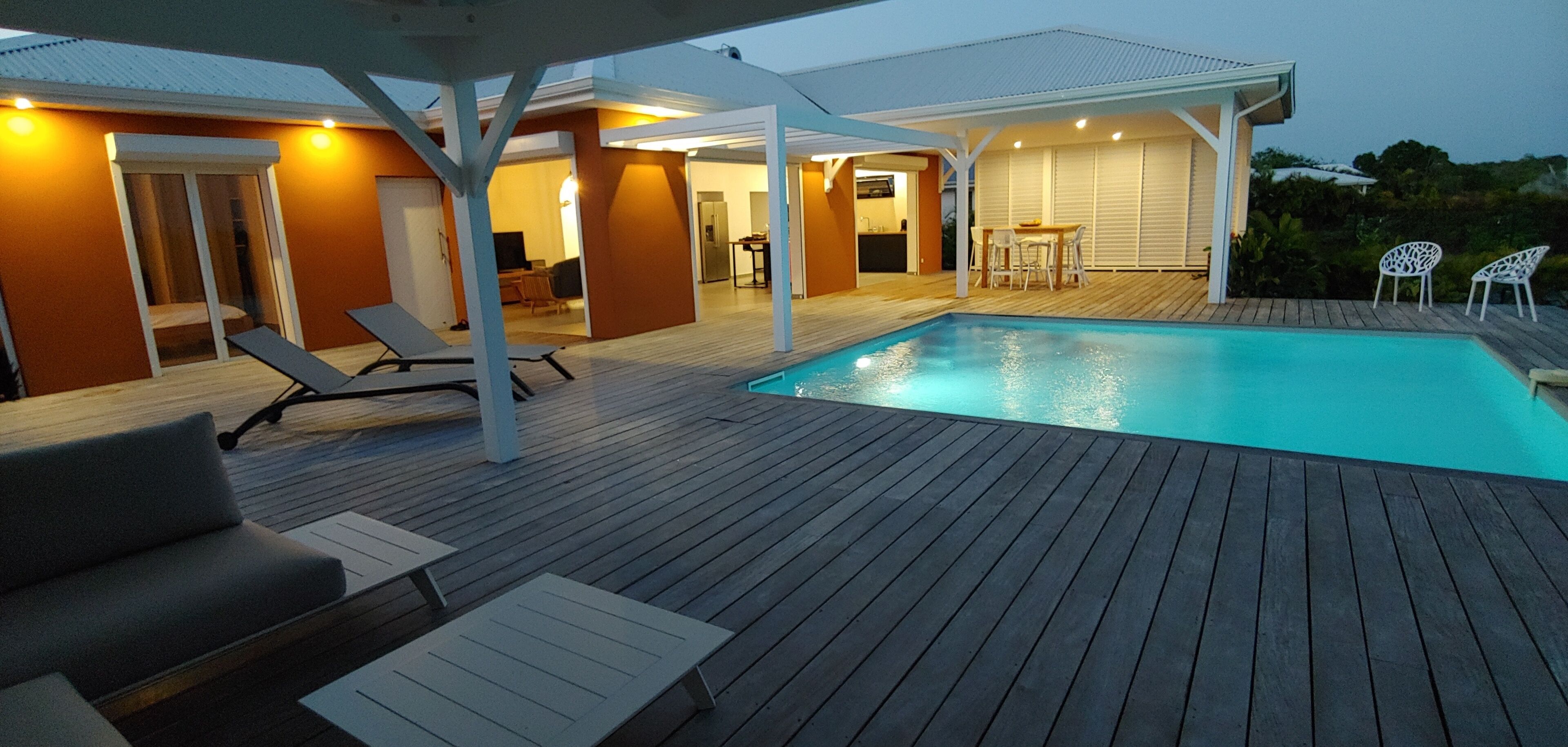 A modern outdoor pool area with lounge chairs and a covered seating area.