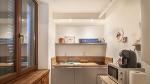 A compact kitchen with a wooden countertop, a built-in sink, a microwave, and a coffee machine.