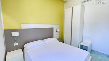 A hotel room with a bed, bedside tables, and a wall-mounted air conditioning unit.