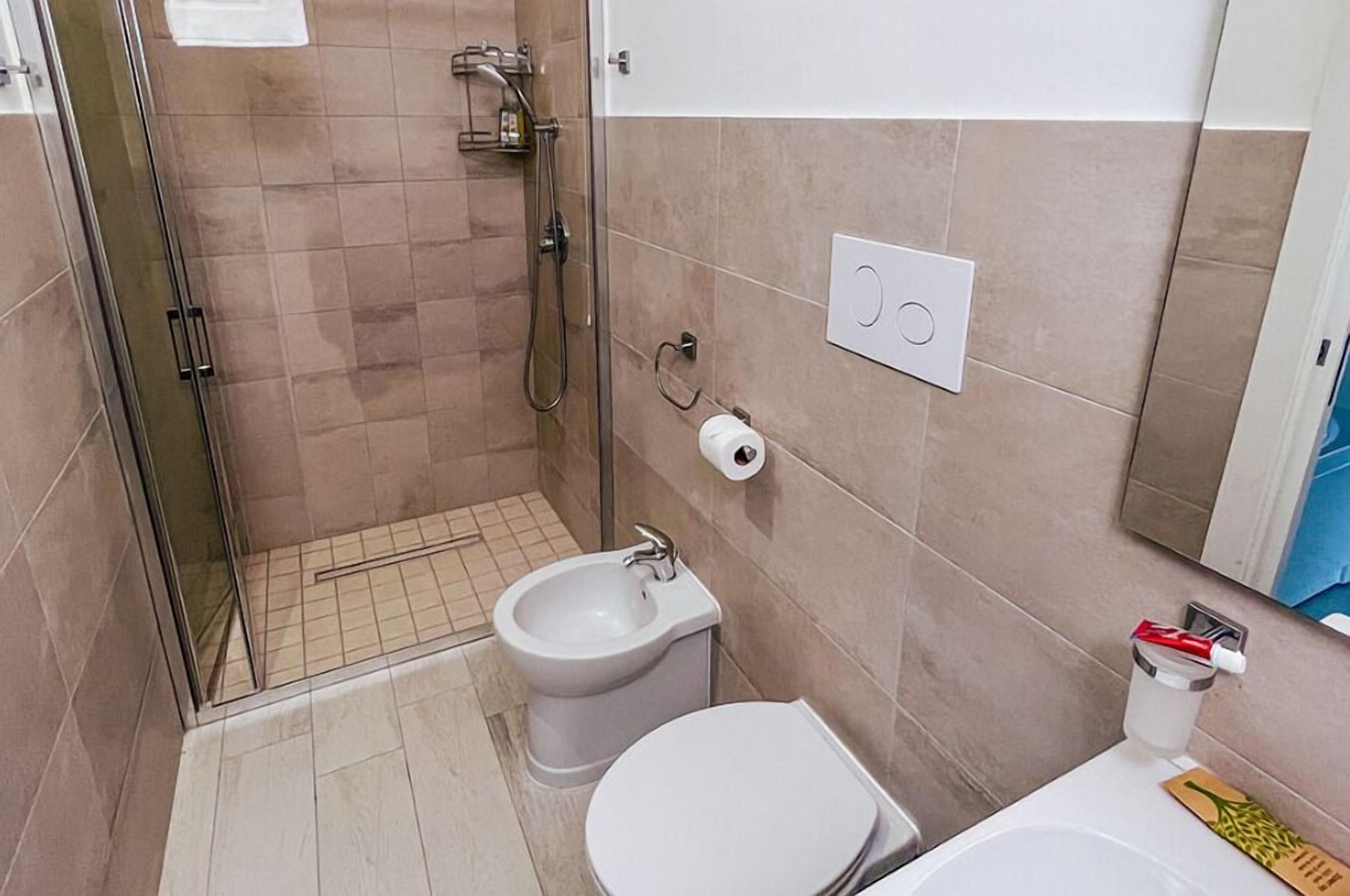 A compact bathroom with a shower, bidet, toilet, and a small sink.
