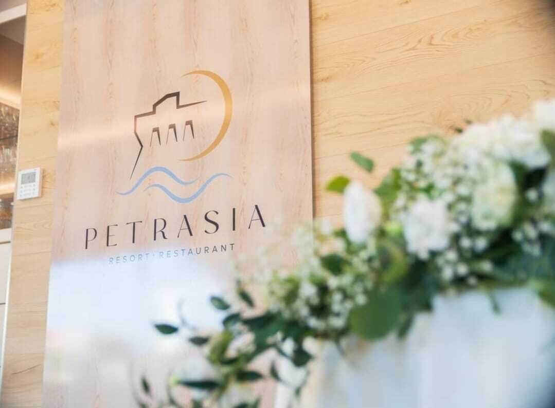 A wooden wall with a logo and text for 'PETRASIA RESORT RESTAURANT'.