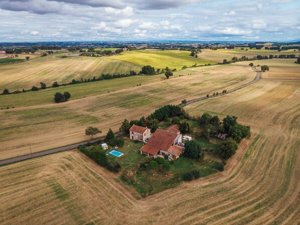 An aerial view of a rural property with fields, a house, and a swimming pool.