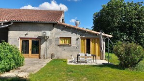 A stone house with a tiled roof, a satellite dish, and a patio with outdoor furniture.
