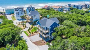 A coastal residential area with houses, a clear view of the ocean, and a location pin indicating a specific house.