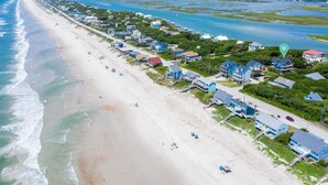 A coastal residential area with beachfront properties, a road, and a beach.