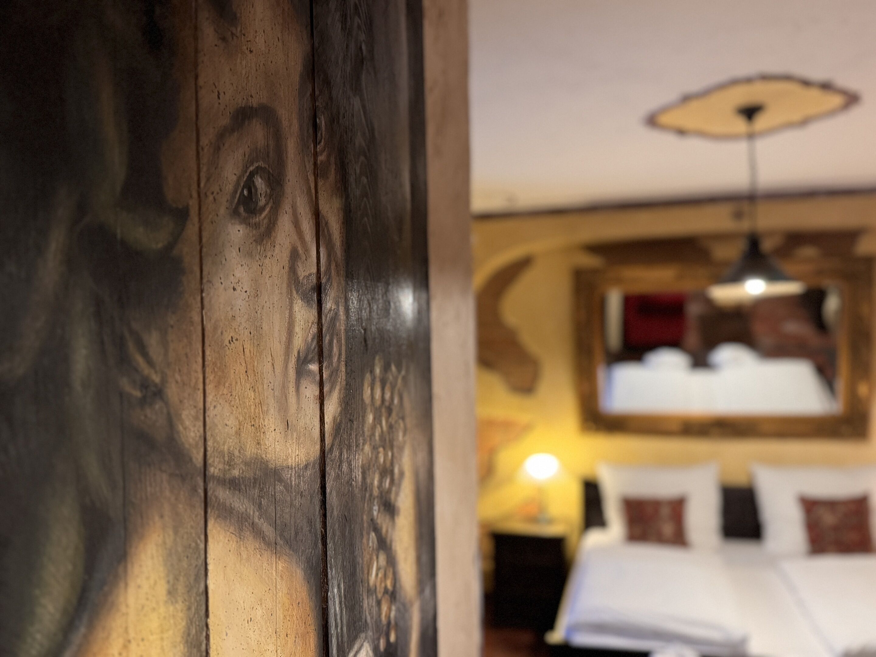 Een kamer met een bed, een lamp en een schilderij aan de muur.