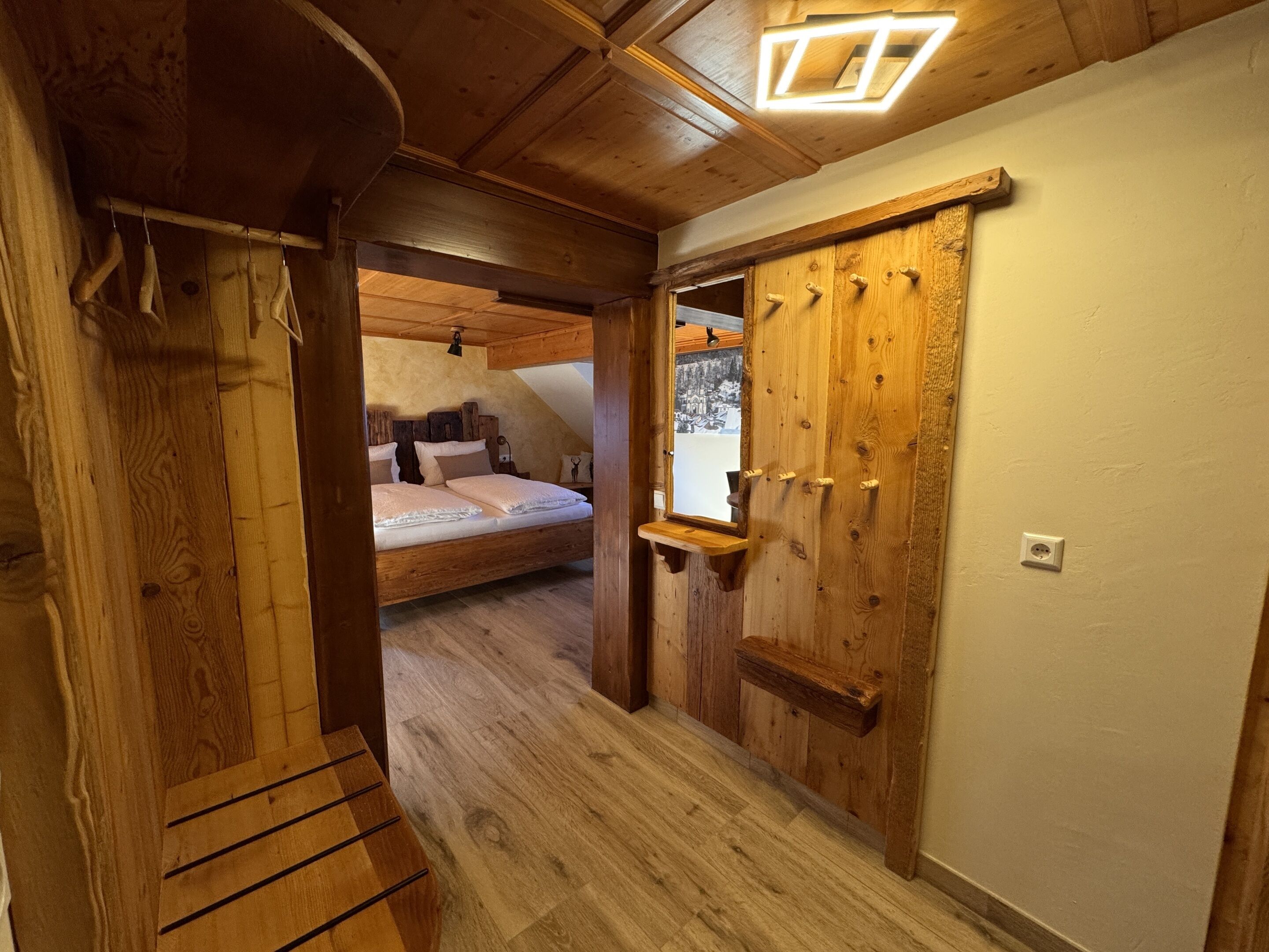 A wooden interior with a loft bedroom, wooden wardrobe, and a bench.