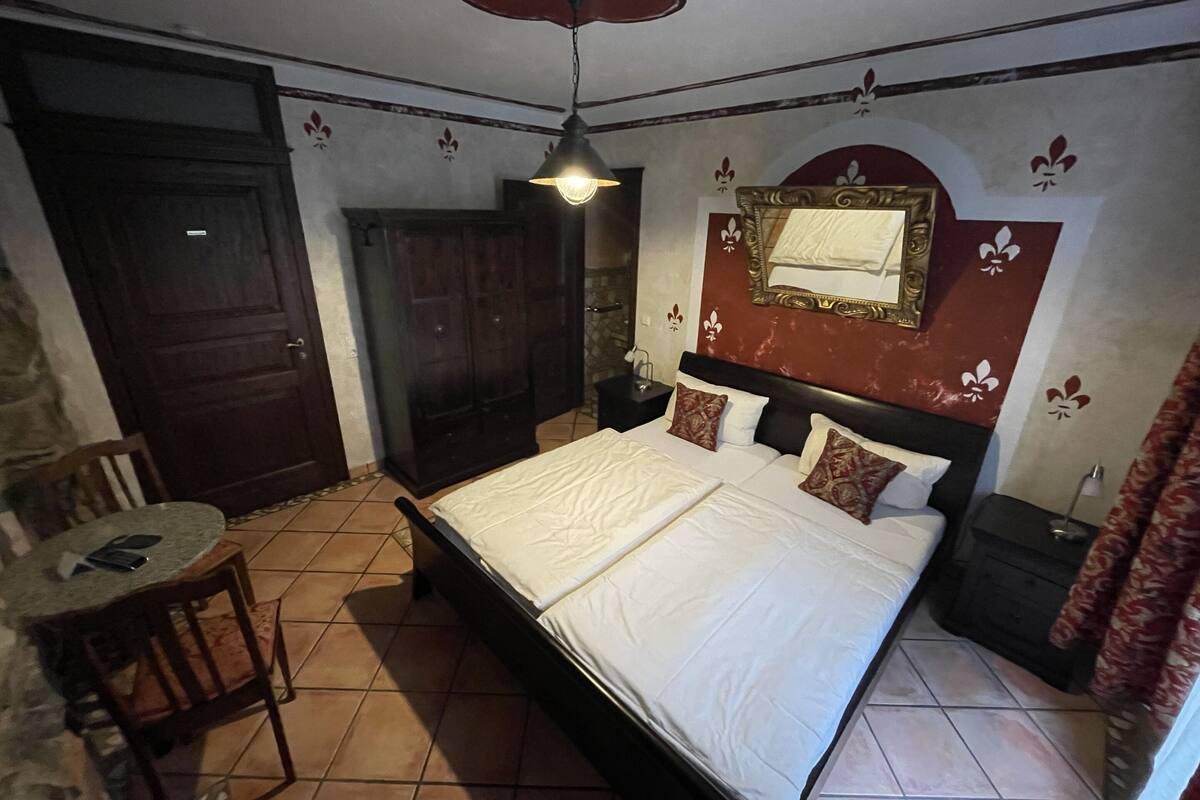Un dormitorio con cama, una silla, una mesa y un armario.