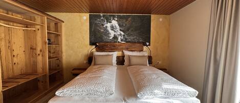 Un dormitorio de madera con una cama, dos almohadas, un cabecero y un cuadro de una cascada.