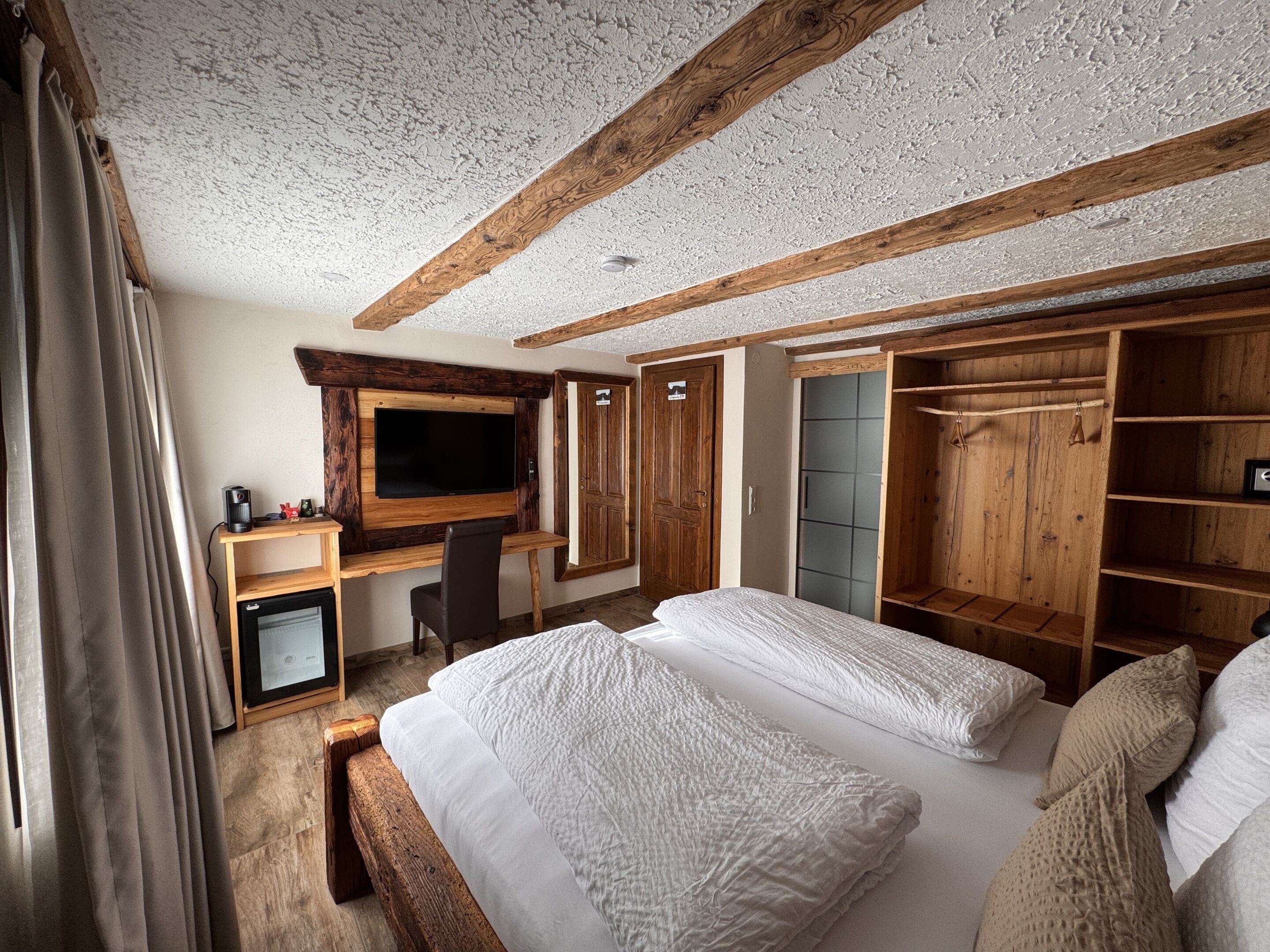 Un dormitorio con una cama grande, un escritorio con televisor, un armario y un mueble auxiliar.