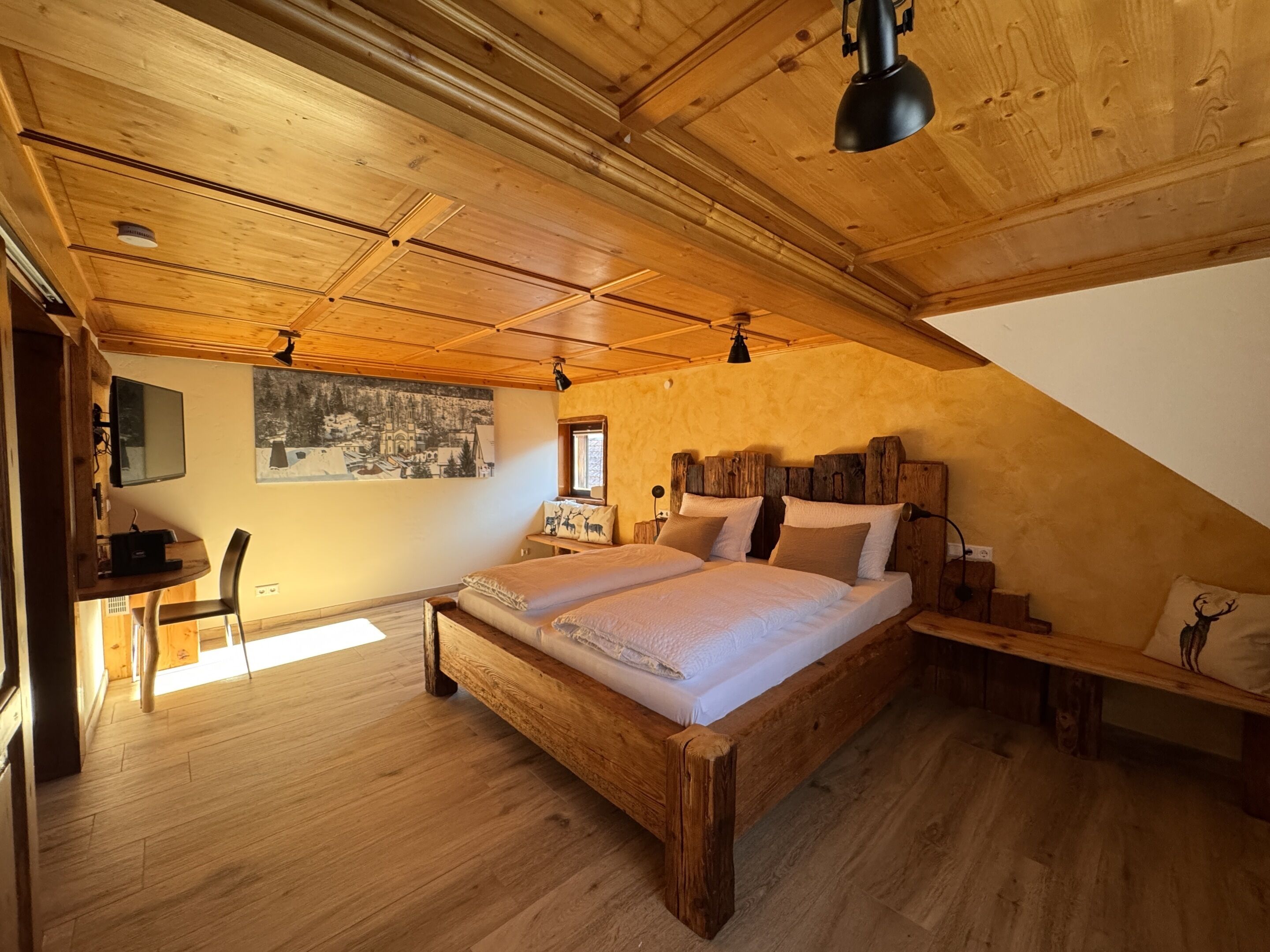 Une chambre mansardée chaleureuse, avec un lit en bois, un bureau et une chaise.